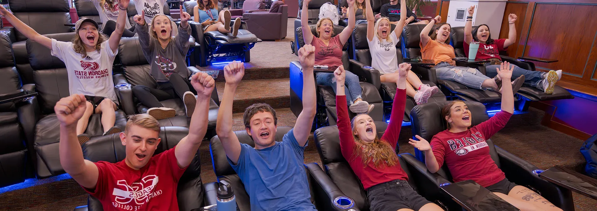 Large group of students watching a game on television and cheering